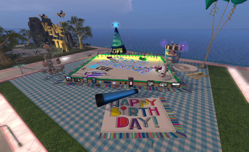 Viewed from about 20 meters up, a broad blue and white gingham cloth covers most of the parcel. In the foreground, a blue celebratory horn and "Happy Birth Day!" napkin bordered in bright colours sit. A low platform sits in the middle of the parcel resembling a giant sheet cake labeled "Happy Birthday Second Life". Panels with pictures line the near side of the platform. In the background, a birthday party hat and container of ice cream sit. Off to the left is a rack of cupcakes.